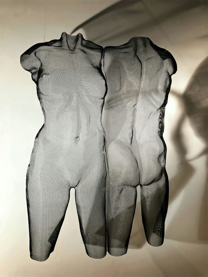 A modern torso sculpture of a girl and a boy in black colour with shadow projections