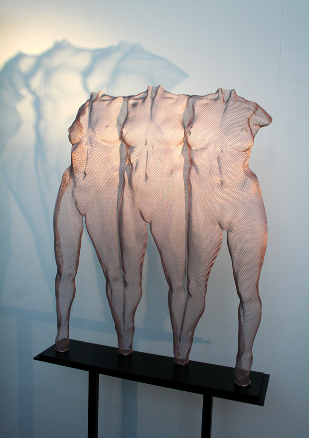 Three girl bodies as a sculpture composition in wire mesh