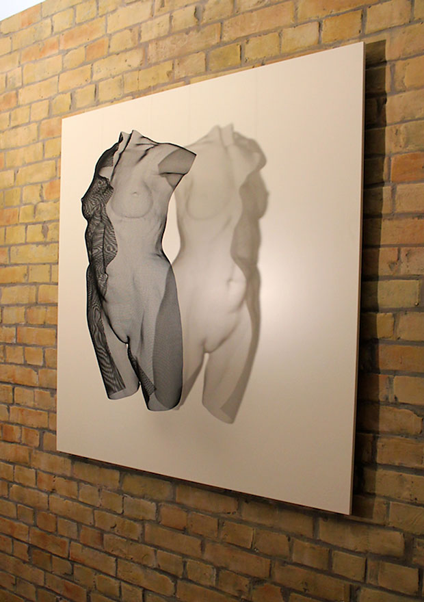 A black modern female torso sculpture displayed on a white screen